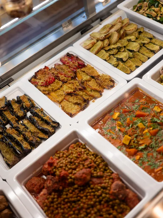 La vetrina del banco con le teglie di gastronomia: verdure gratinate, melanzane, piselli in umido