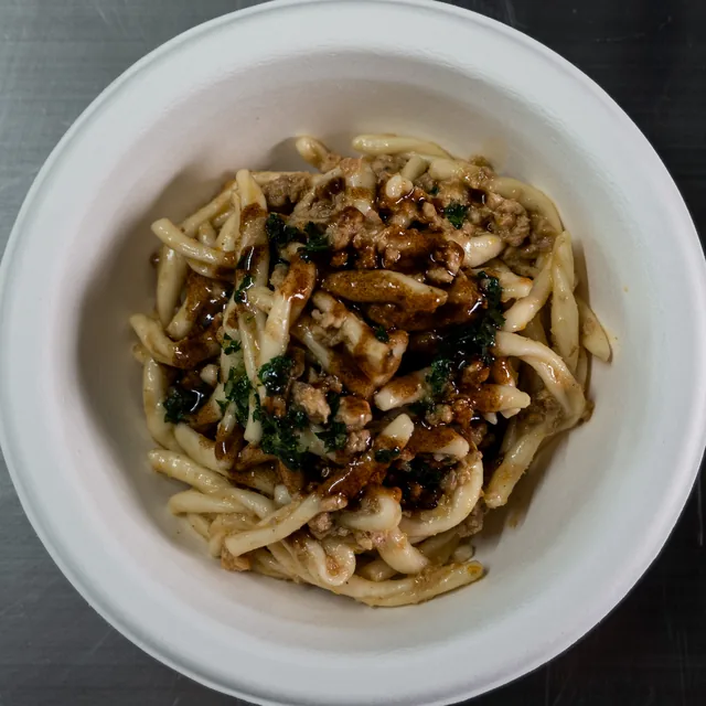 Strozzapreti al ragù di cortile nella ciotola bianca, visti dall'alto