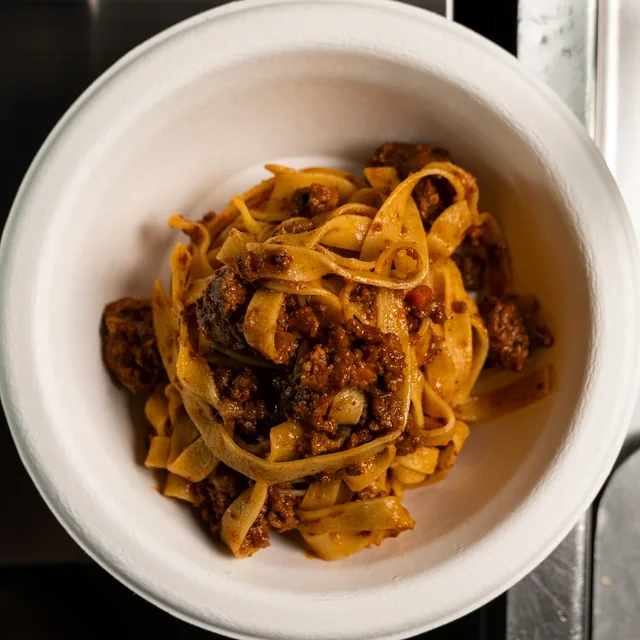 Tagliatelle al ragù nella ciotola bianca, viste dall'alto